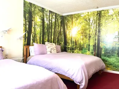two beds in a bedroom with a mural of a forest at Lotus Family Suite w 2 Beds Kitchenette 4 in Shandaken