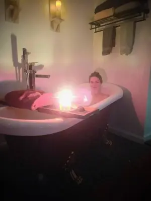 a woman laying in a bath tub with a candle at Guest Favorite Garuda Apartment 8 in Shandaken