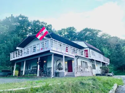 a large white house with a flag on top of it at Catskill Cabin Little Owl Apt 1 in Shandaken