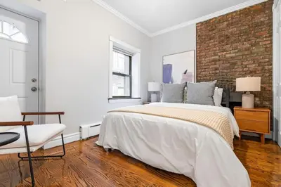 a bedroom with a large bed and a brick wall at Gorgeous & Bright 3BDR & 1BTH in Midtown Manhattan in New York