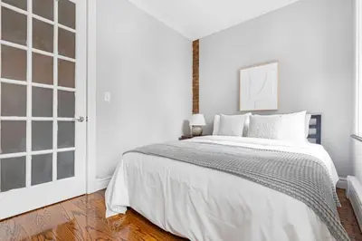 a white bedroom with a bed and a window at Gorgeous & Bright 3BDR & 1BTH in Midtown Manhattan in New York