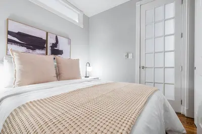 a white bedroom with a large bed with pillows at Gorgeous & Bright 3BDR & 1BTH in Midtown Manhattan in New York