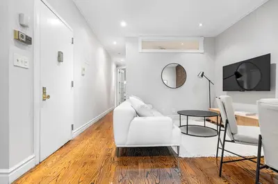 a white living room with a white couch and a table at Gorgeous & Bright 3BDR & 1BTH in Midtown Manhattan in New York