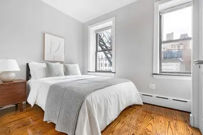 a white bedroom with a bed and two windows at Gorgeous & Bright 3BDR & 1BTH in Midtown Manhattan in New York