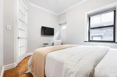 a white bedroom with a bed and a tv at Gorgeous & Bright 3BDR & 1BTH in Midtown Manhattan in New York