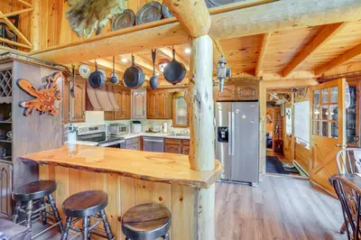 a kitchen with wooden cabinets and a counter with stools at Elegant Hudson Valley Retreat with Hot Tub and Pond in Austerlitz