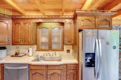 a kitchen with wooden cabinets and a white refrigerator at Elegant Hudson Valley Retreat with Hot Tub and Pond in Austerlitz