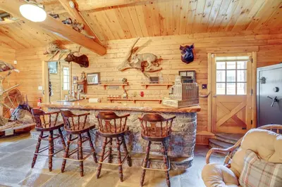 a log cabin kitchen with a bar and stools at Elegant Hudson Valley Retreat with Hot Tub and Pond in Austerlitz