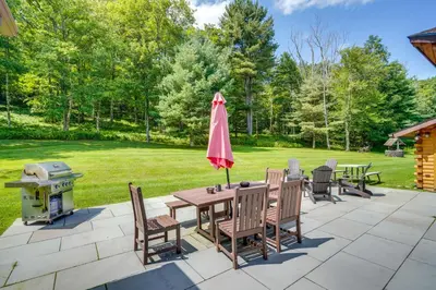 a patio with a table with an umbrella and a grill at Elegant Hudson Valley Retreat with Hot Tub and Pond in Austerlitz