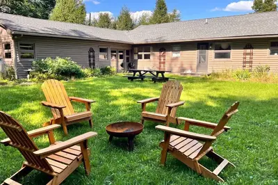 three wooden chairs and a table in a yard at The Mod Cabin in Bearsville