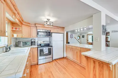 a kitchen with wooden cabinets and white appliances at Pet-Friendly Home with Beach in Northville! in Northville