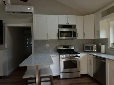 a kitchen with white cabinets and stainless steel appliances at Lovely private home in a serene neighborhood in Totowa