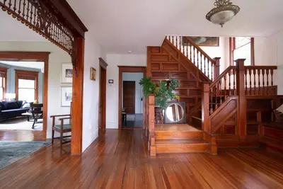 a living room with a wooden staircase in a house at Dancing Doe Estate - Delaware Valley Escape with Wood Stove and Hot Tub in Jeffersonville