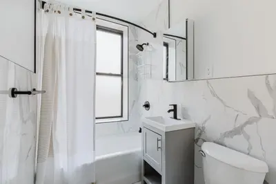 a white bathroom with a sink toilet and a window at Blueground Greenpoint wd ac near ferry NYC-1538 in New York