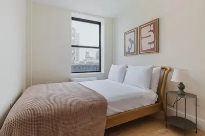 a bedroom with a bed with white sheets and a window at Blueground Greenpoint wd ac near ferry NYC-1538 in New York