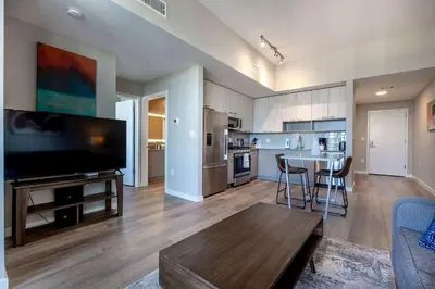 a living room with a table and a kitchen at Trendy Apt On Harbor with Gym in Stamford