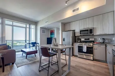 a kitchen and living room with a table and chairs at Trendy Apt On Harbor with Gym in Stamford