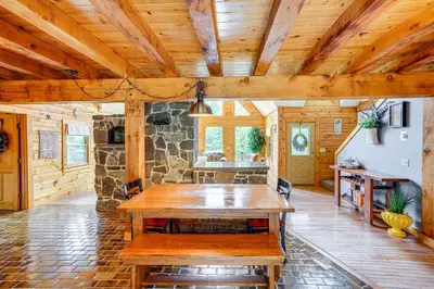 a dining room with a wooden table and a stone wall at Spacious Wilmington Cabin Walk to Lake in Wilmington