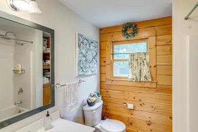 a bathroom with a toilet and a window at Spacious Wilmington Cabin Walk to Lake in Wilmington