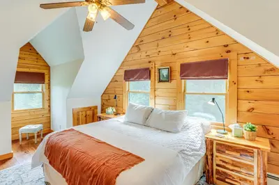 a bedroom with a bed and a ceiling fan at Spacious Wilmington Cabin Walk to Lake in Wilmington