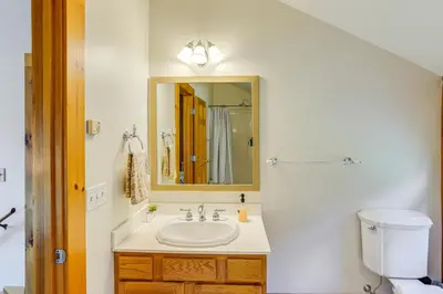 a bathroom with a sink and a mirror and a toilet at Spacious Wilmington Cabin Walk to Lake in Wilmington