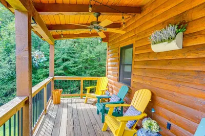 a wooden deck with chairs and a ceiling fan at Spacious Wilmington Cabin Walk to Lake in Wilmington
