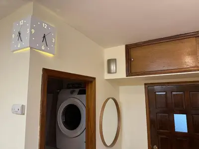 a bathroom with a washing machine and a clock on the wall at Sunny Apt by the park Mins away from midtown New York in Jersey City