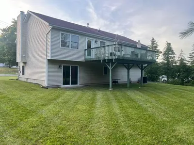 a house with a deck on top of a yard at Cozy Beautiful Pondside Luxurious Retreat in Monroe