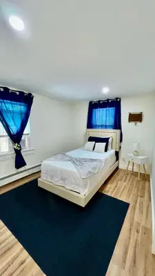a bedroom with a bed and blue curtains at Spacious 4BR home w 2BA, a workspace & king bed! in Fort Plain