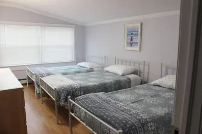 a bedroom with three beds and a window at Pet Friendly Milford Beachfront Home in Stratford