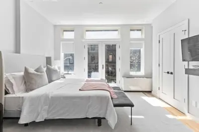 a white bedroom with a large bed and windows at Luxe Studio w Juliet Balcony in Upper East in New York
