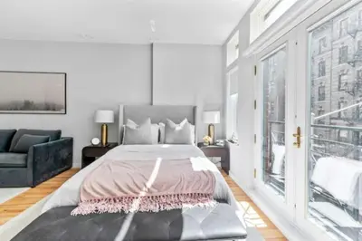 a white bedroom with a bed and a couch at Luxe Studio w Juliet Balcony in Upper East in New York