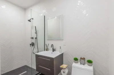 a white bathroom with a sink and a shower at Luxe Studio w Juliet Balcony in Upper East in New York
