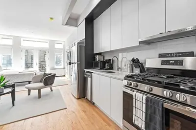 a kitchen with a stove and a living room at Luxe Studio w Juliet Balcony in Upper East in New York