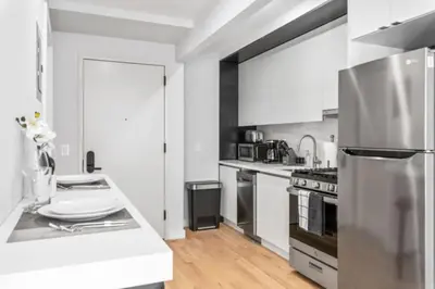 a kitchen with white cabinets and a stainless steel refrigerator at Luxe Studio with Charming Juliet Balcony in New York