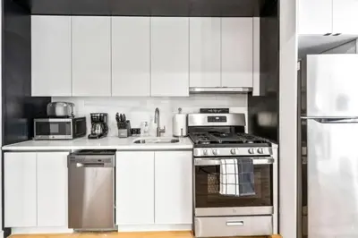 a kitchen with white cabinets and a stove top oven at Luxe Studio with Charming Juliet Balcony in New York