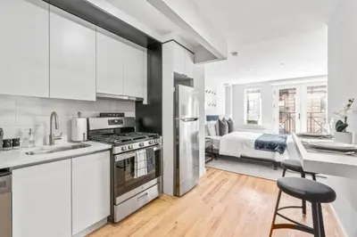 a kitchen with white cabinets and a bed in a room at Luxe Studio with Charming Juliet Balcony in New York