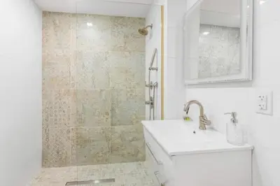 a white bathroom with a sink and a shower at Luxe Studio with Charming Juliet Balcony in New York