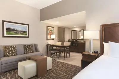 a hotel room with a bed and a couch and a desk at Embassy Suites Saratoga Springs in Saratoga Springs