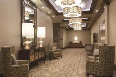 a lobby with chairs and a mirror and lights at Embassy Suites Saratoga Springs in Saratoga Springs