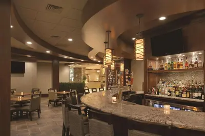 a bar in a restaurant with tables and chairs at Embassy Suites Saratoga Springs in Saratoga Springs