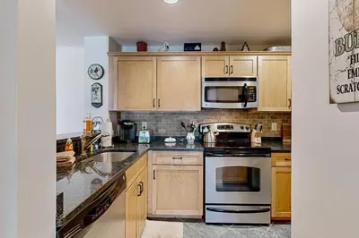 a kitchen with wooden cabinets and stainless steel appliances at The Seasons G27 in Dover