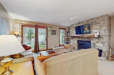 a living room with a stone fireplace and a tv at The Seasons G17 in West Dover