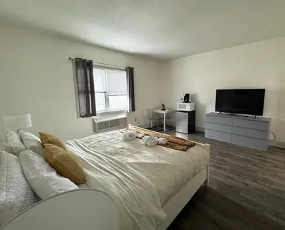 a white bedroom with a bed and a television at Solano Inn in Portland