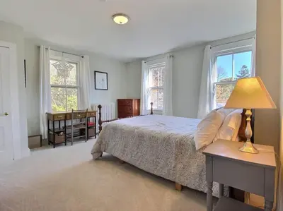 a bedroom with a bed and a table with a lamp at Historic Colonial Pool Walk to Town in Litchfield