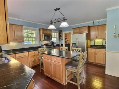 a kitchen with wooden cabinets and a large island at Historic Colonial Pool Walk to Town in Litchfield
