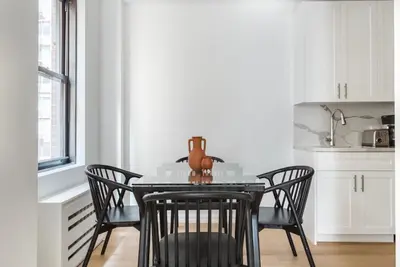 a dining room table with chairs and a vase on it at Blueground Midtown gym elev nr Grand Central NYC-1479 in New York