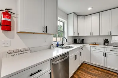 a kitchen with white cabinets and a red fire extinguisher at 1 Mi to MGM Springfield Cozy Winter Duplex! in Springfield