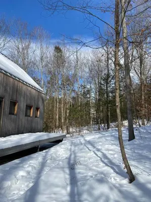 a snow covered yard with a bench and a building at Modern Mountain Retreat in Mount Tremper