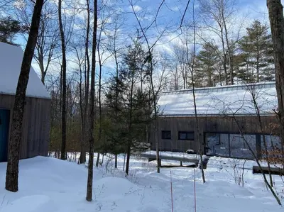 a building in the snow next to some trees at Modern Mountain Retreat in Mount Tremper